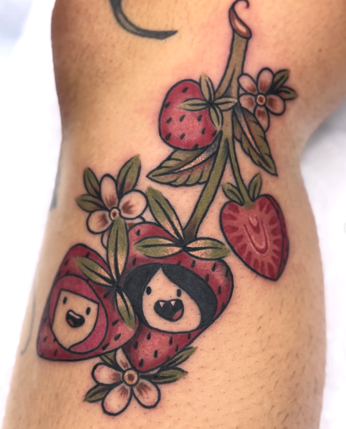 A colorful tattoo of strawberries, flowers, and cute faces on the skin.