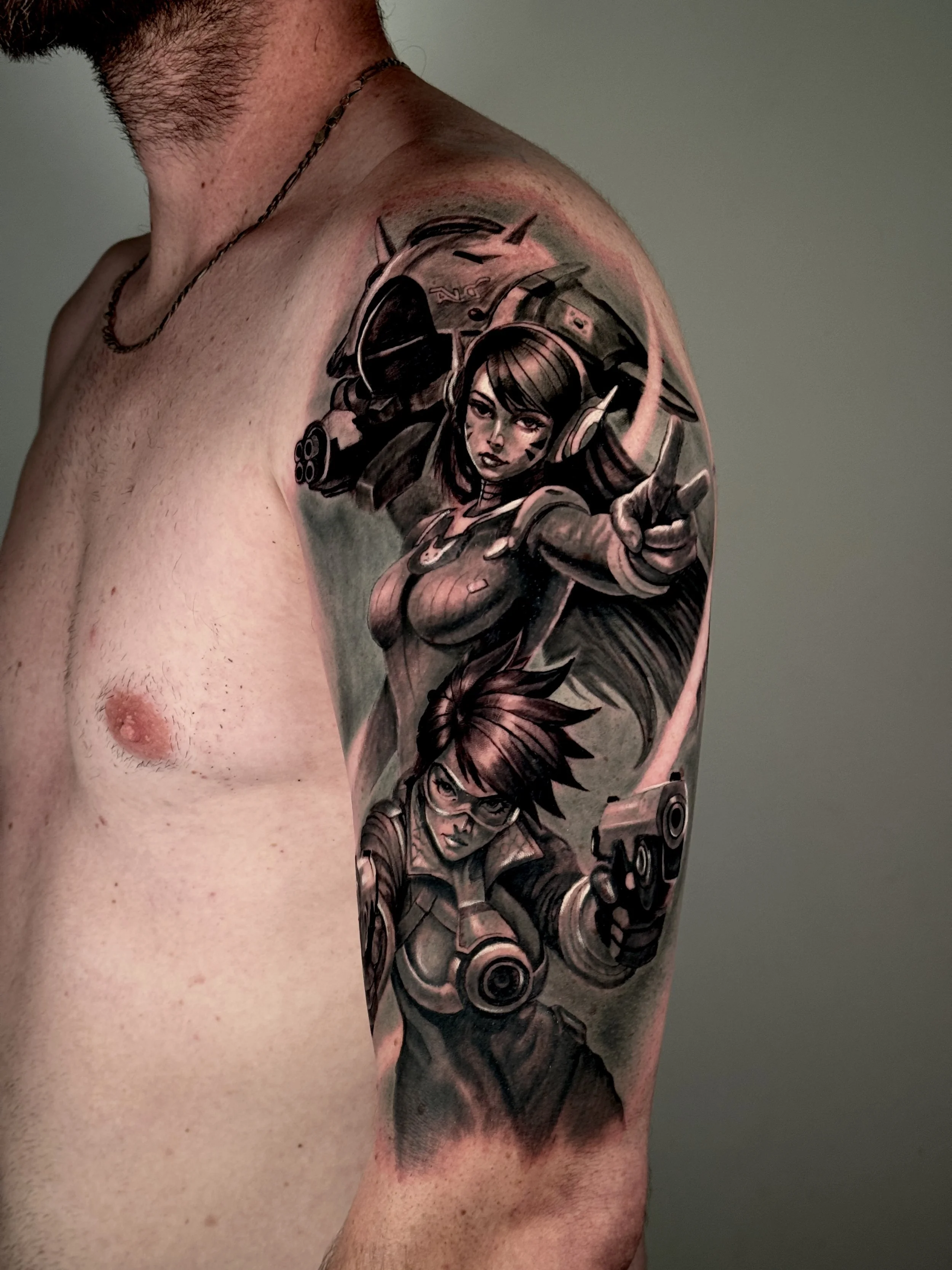 A tattoo of a woman wearing a helmet and holding a weapon on her shoulder, in manga style, in black and gray, on a man's arm.