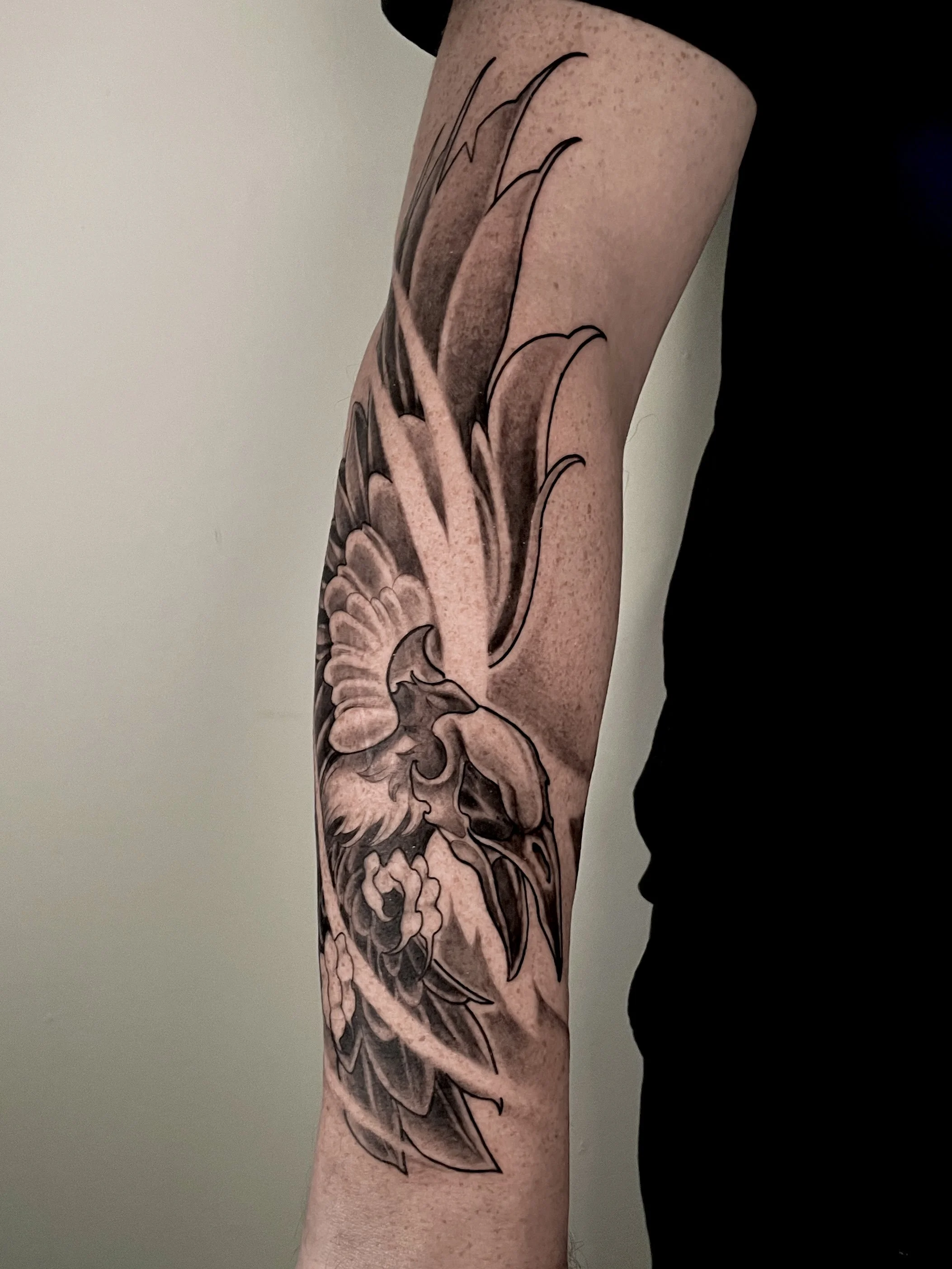 Tatouage en noir de formes florales et de vagues sur le bras d'une personne