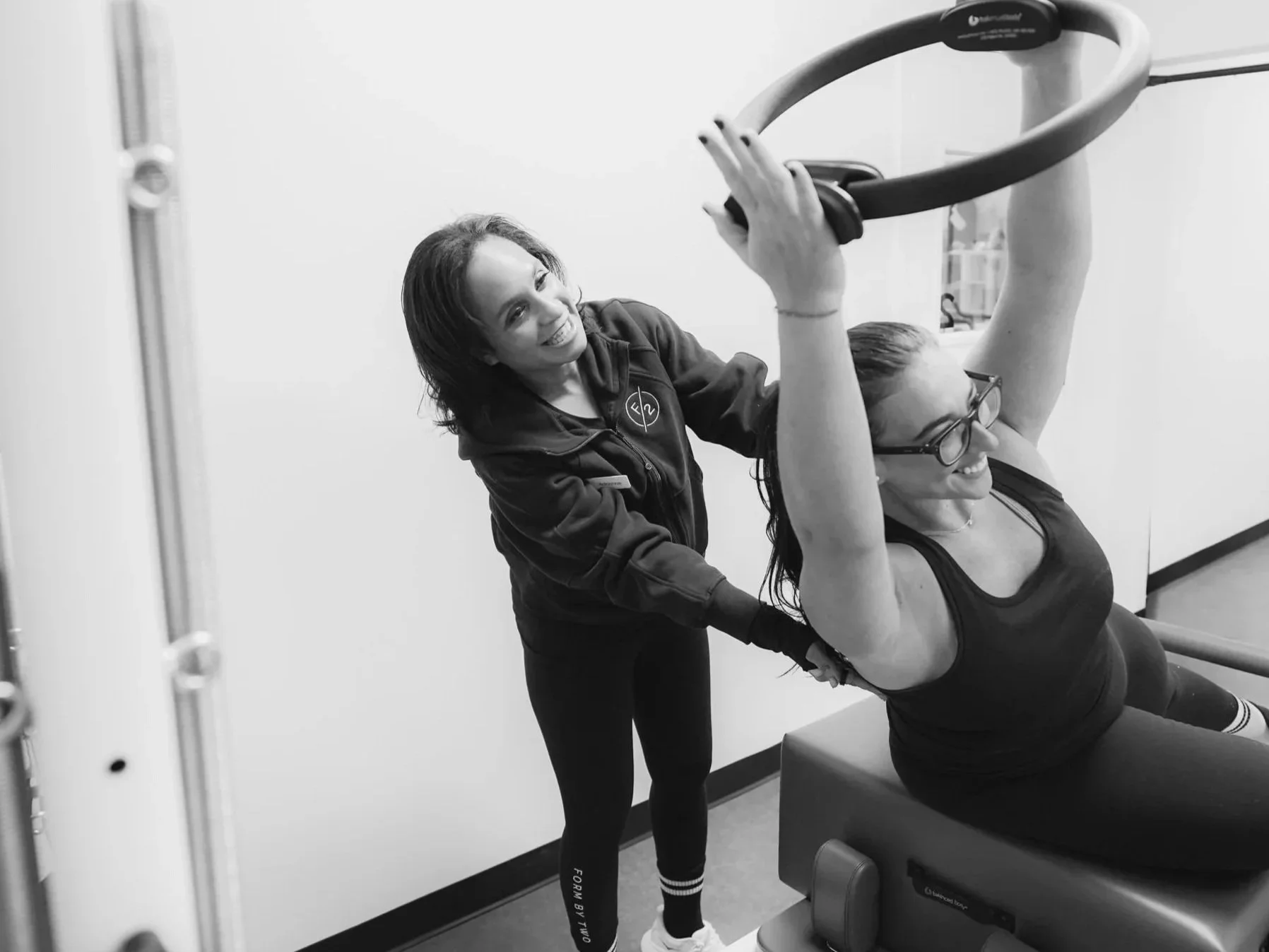 Fitness instructor and FORM BY TWO member working out on the pilates reformer with a pilates ring.