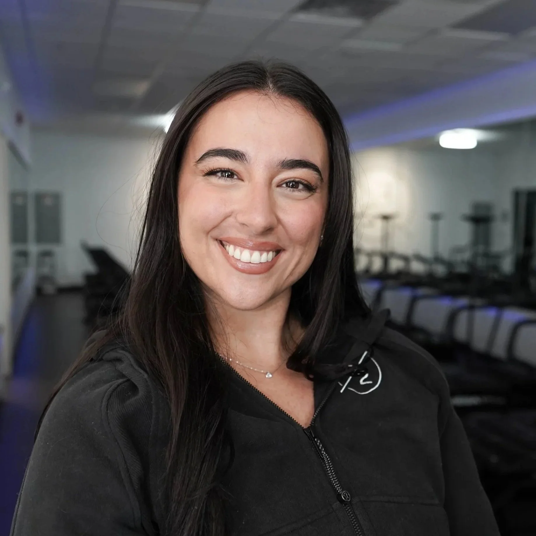 Client of FORM BY TWO smiling in front of Megaformer machines.