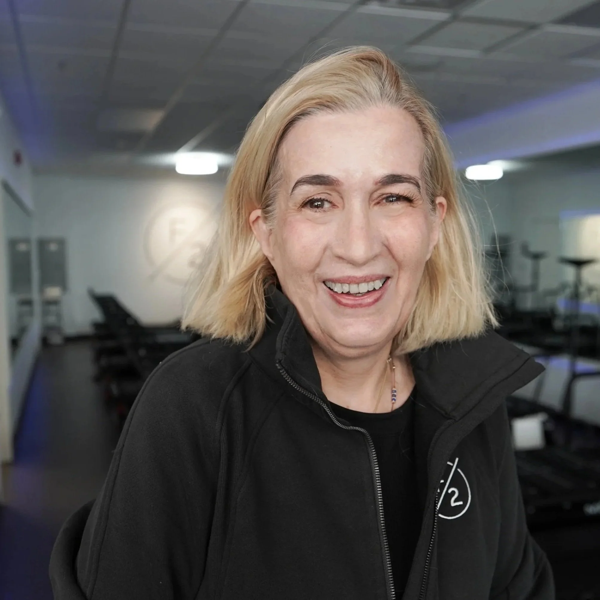 Client of FORM BY TWO smiling in front of Megaformer machines.