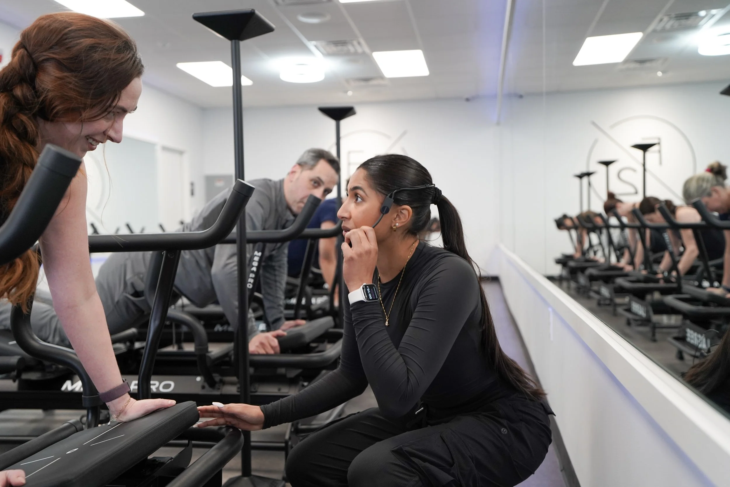 A fitness instructor providing guidance to a woman during a Lagree workout.