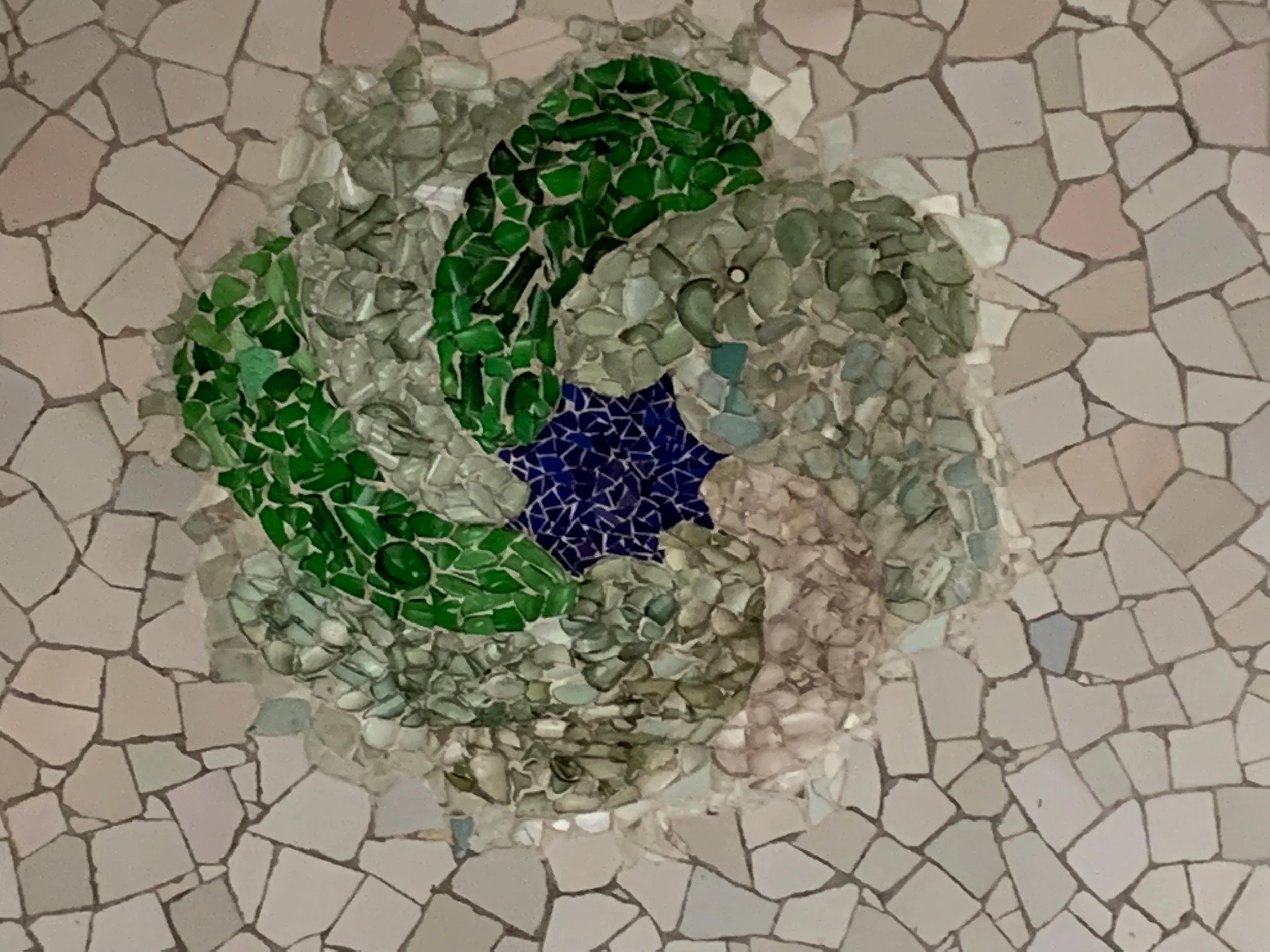 Mosaic artwork with the Texas flag design on the ground, surrounded by a pattern of irregular stone tiles.