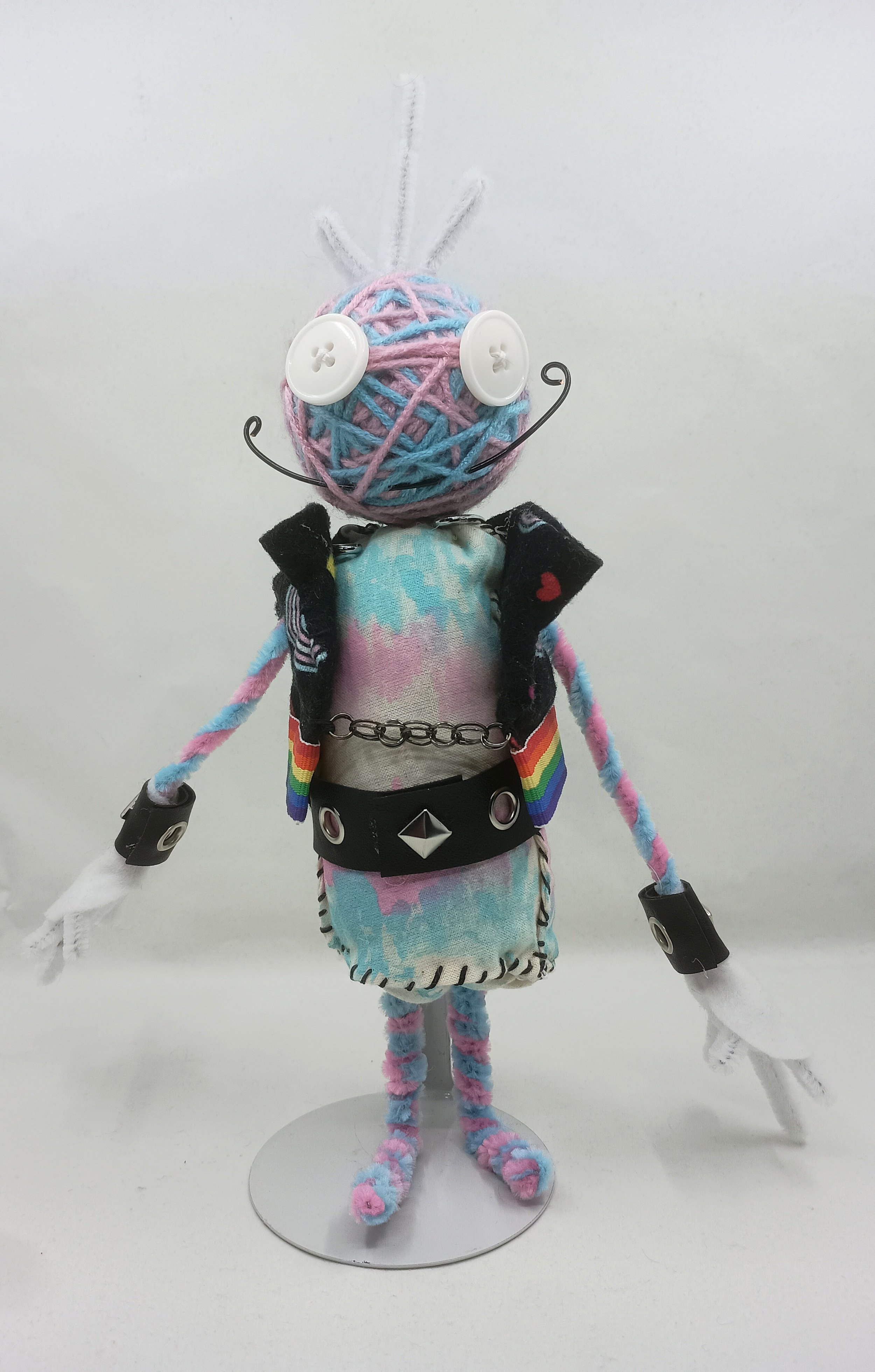 Trans Punk Omni Doll, yarn, buttons, pipe cleaners, acrylic paint, faux leather ribbon, 2025