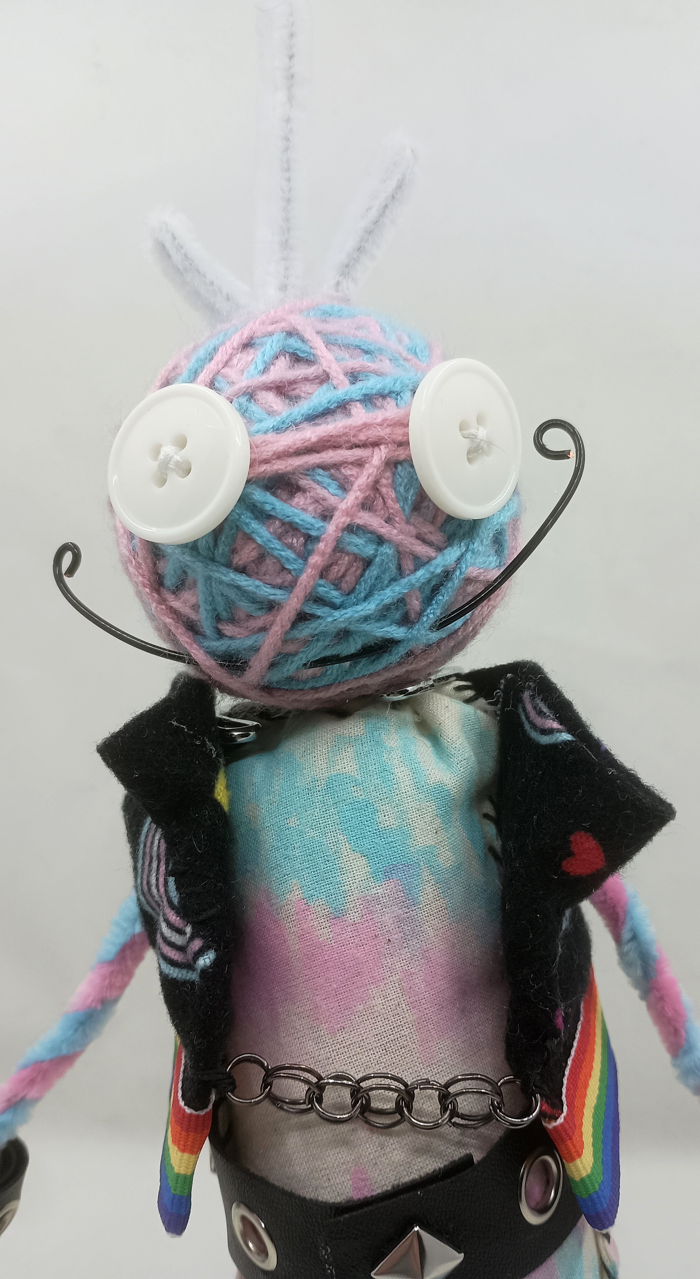 Trans Punk Omni Doll Detail, yarn, buttons, pipe cleaners, acrylic paint, faux leather ribbon, 2025