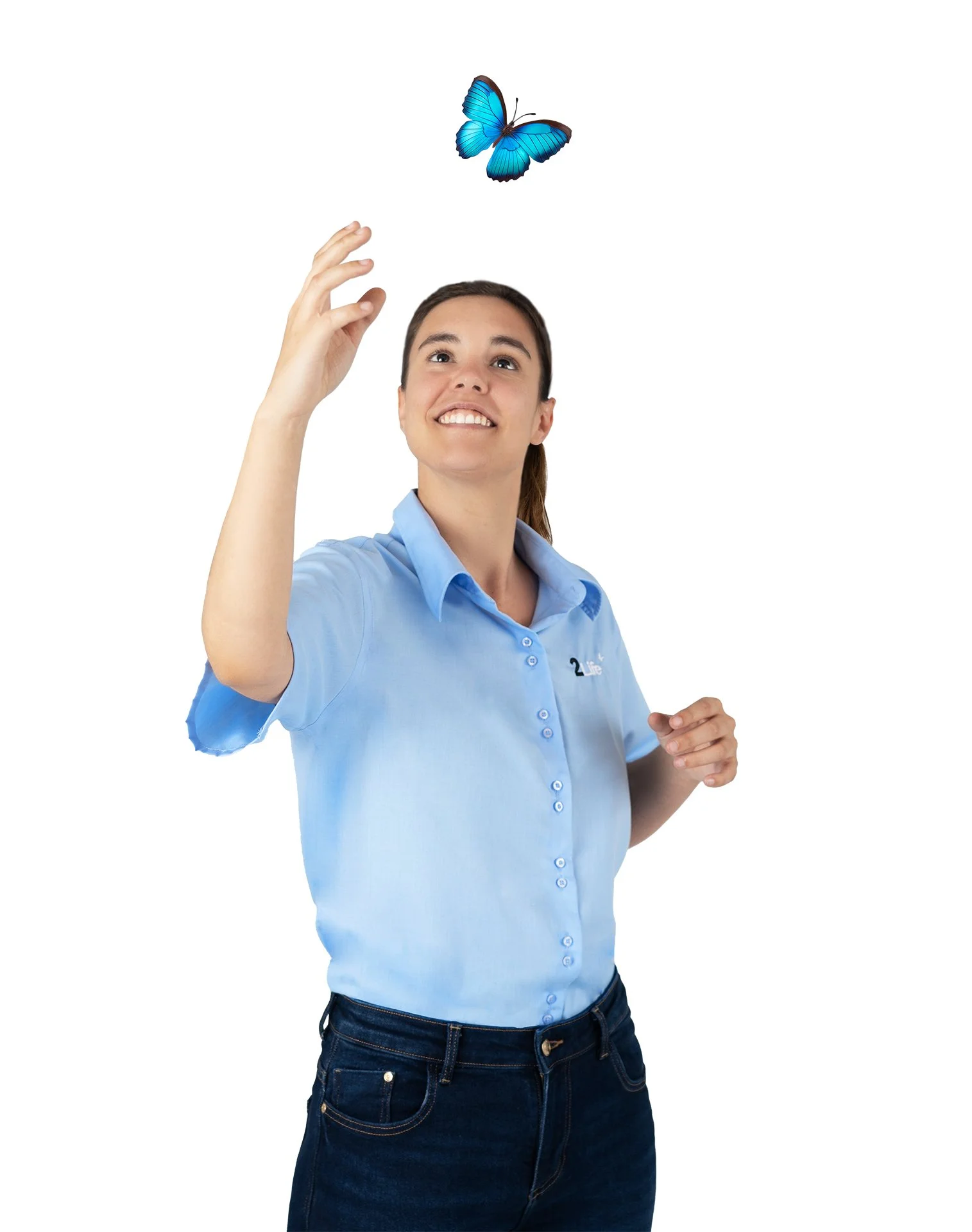 Una mujer joven con blusa azul y pantalones oscuros intenta tocar una mariposa azul que vuela en su mano, con expresión de asombro y alegría.