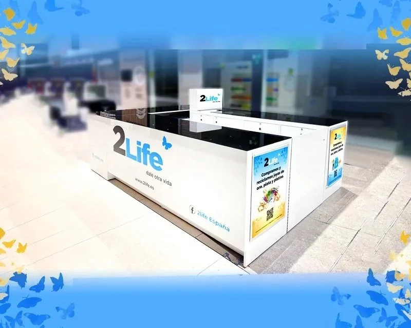 Mesas de reciclaje para botellas y platos de plástico con la marca 2Life y promociones en carteles publicitarios en un centro comercial.