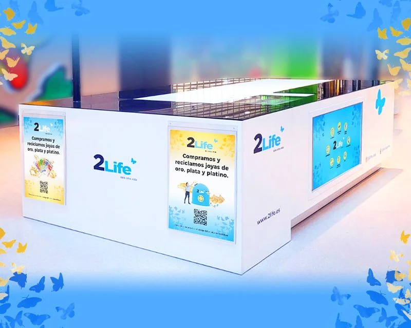 Mostrador de compra y reciclaje de joyas de oro, plata y platino bajo la marca 2Life, con anuncios y una pantalla digital.