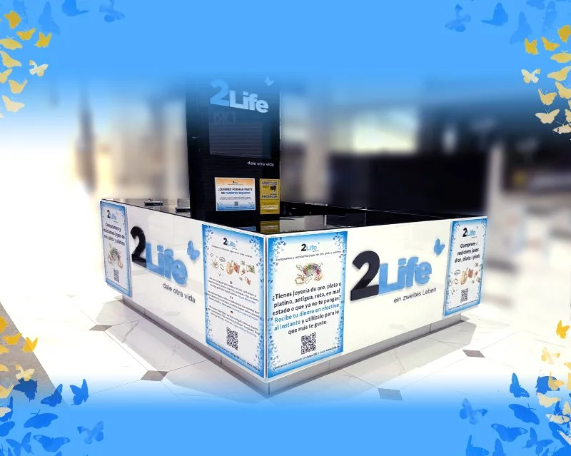 Mostrador de recolección de donaciones para la organización 2 Life, con anuncios que promueven donar joyas en una tienda.