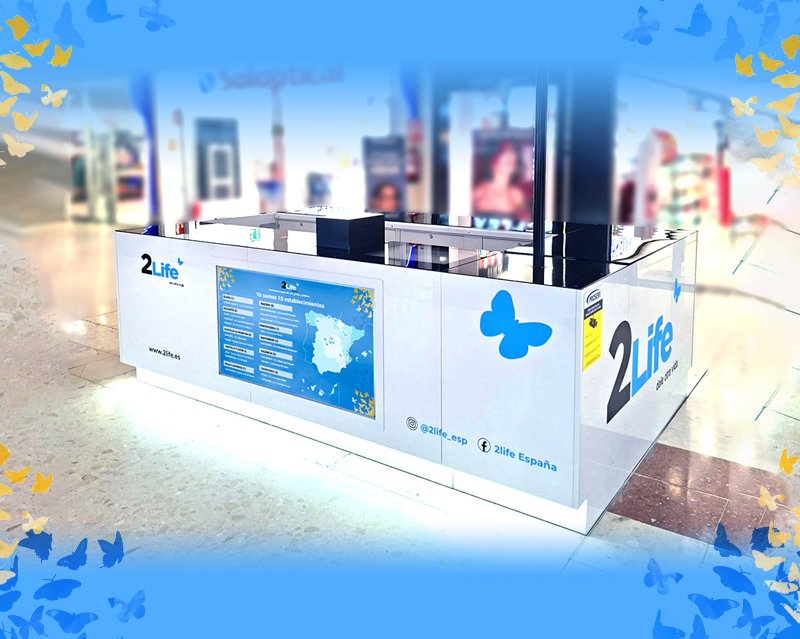 Estación de reciclaje para botellas de plástico en un aeropuerto, decorada con mariposas azules y amarillas, con información en el panel y logo de 2LifE.