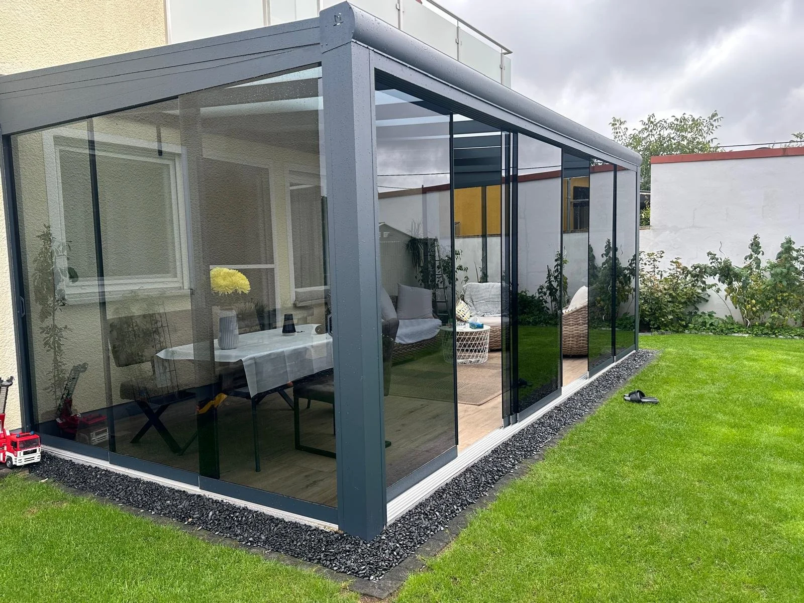 Wintergarten, getönte Glasschiebetüren, pulverbeschichtetes Aluminium im ländlichen Garten, Saarland.