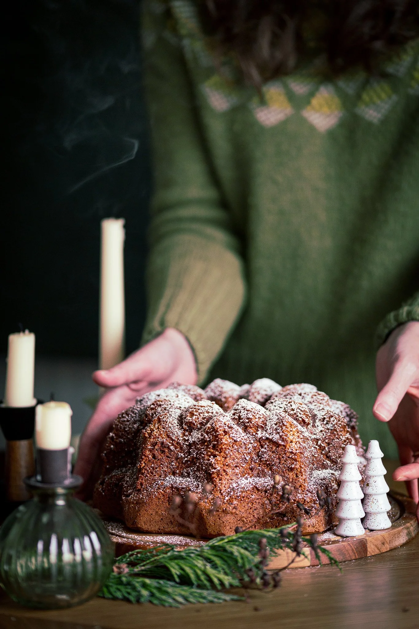 Lifestyle image of a woman serving a chocolate bundt cake with Christmas tree decorations