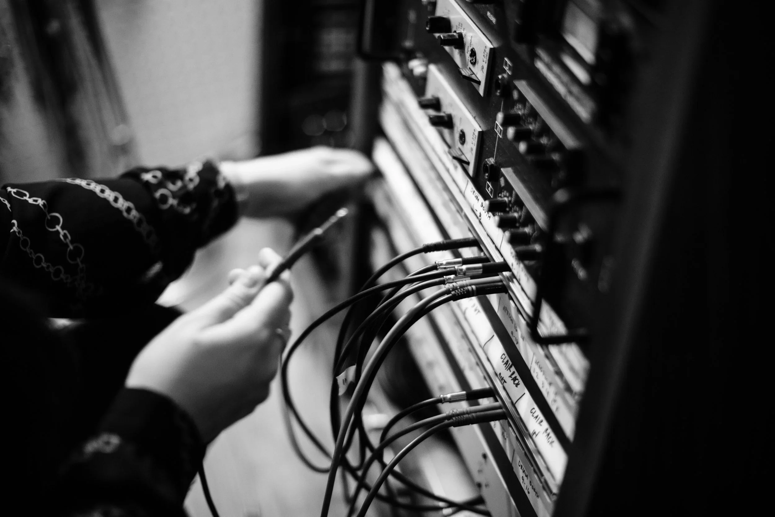 Black and white photo of a person working on an electronic panel, connecting wires to a circuit board