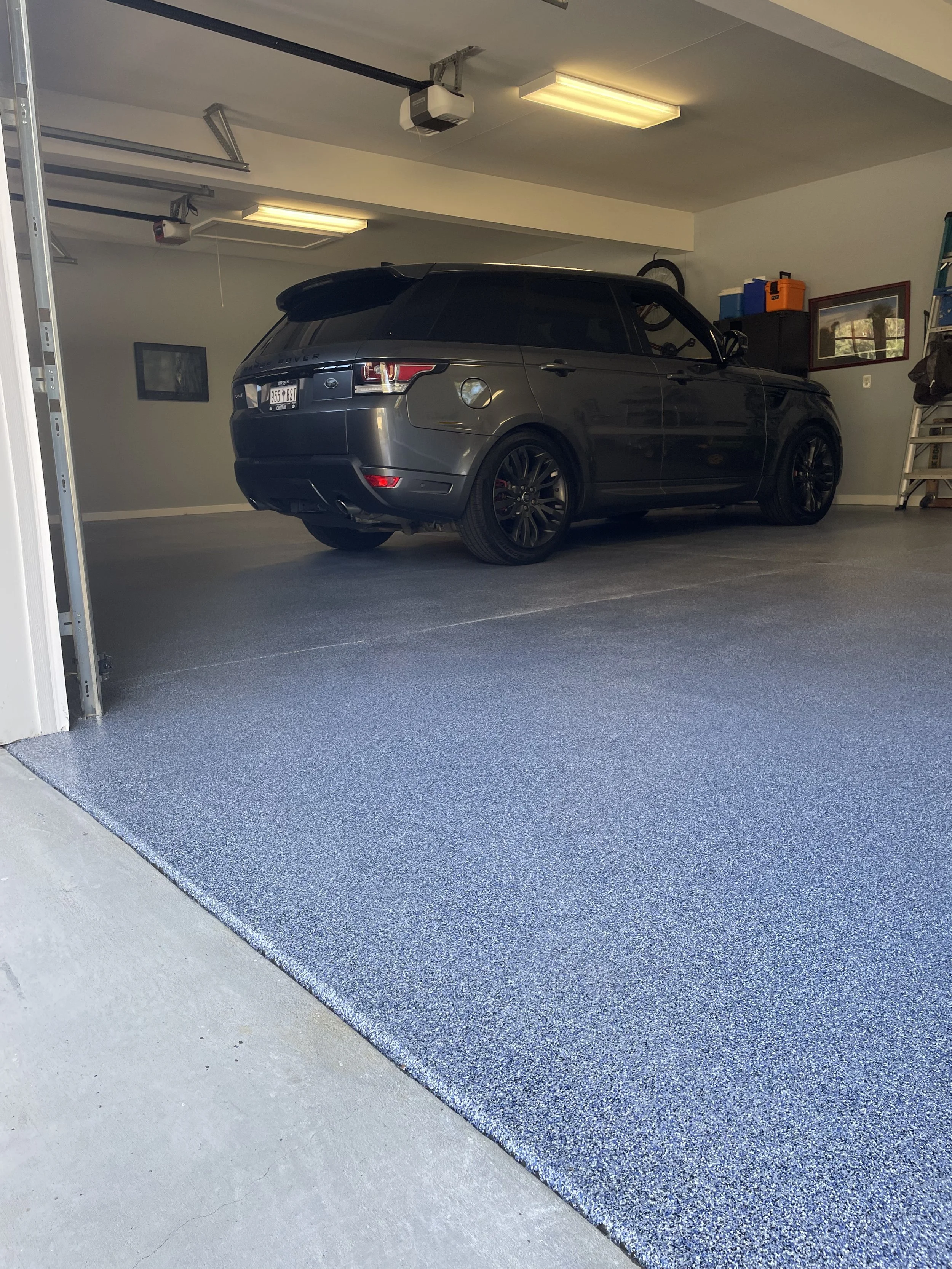 A black Range Rover SUV parked inside a residential garage with a speckled blue floor.