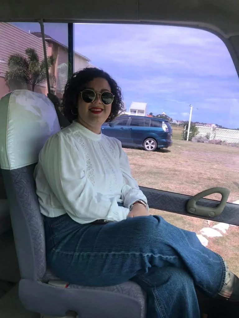 Photo of Camila, smiling with sun glasses on sitting in a coach or bus. Her smile betrays the challenges in getting diagnosed with lung cancer