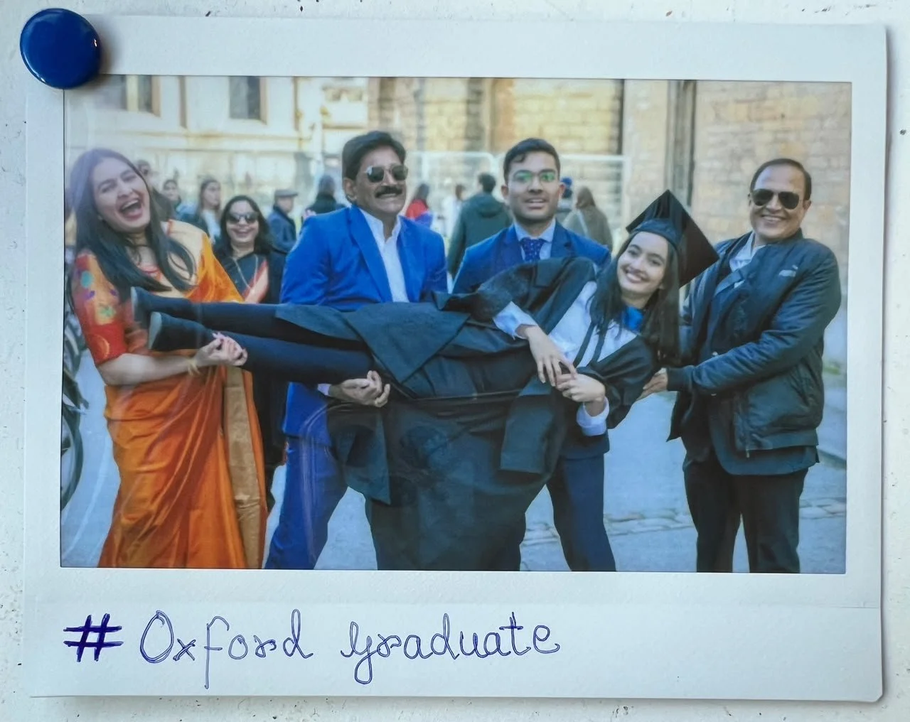 Rasika being carried by group of four - all smiling. Photo says Oxford graduate.