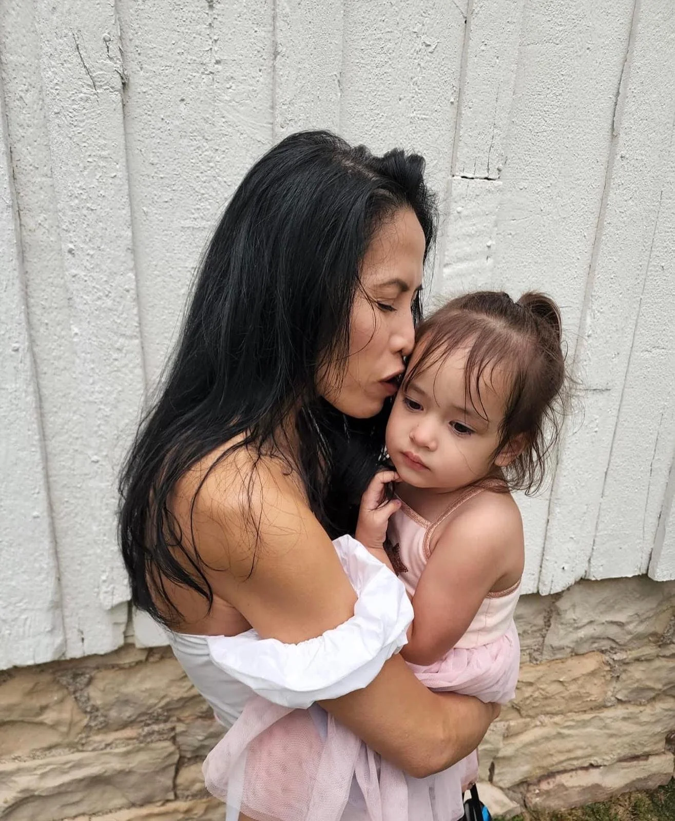 Kimberly, who was diagnosed with ALK+ lung cancer age 52, kisses her young daughter.