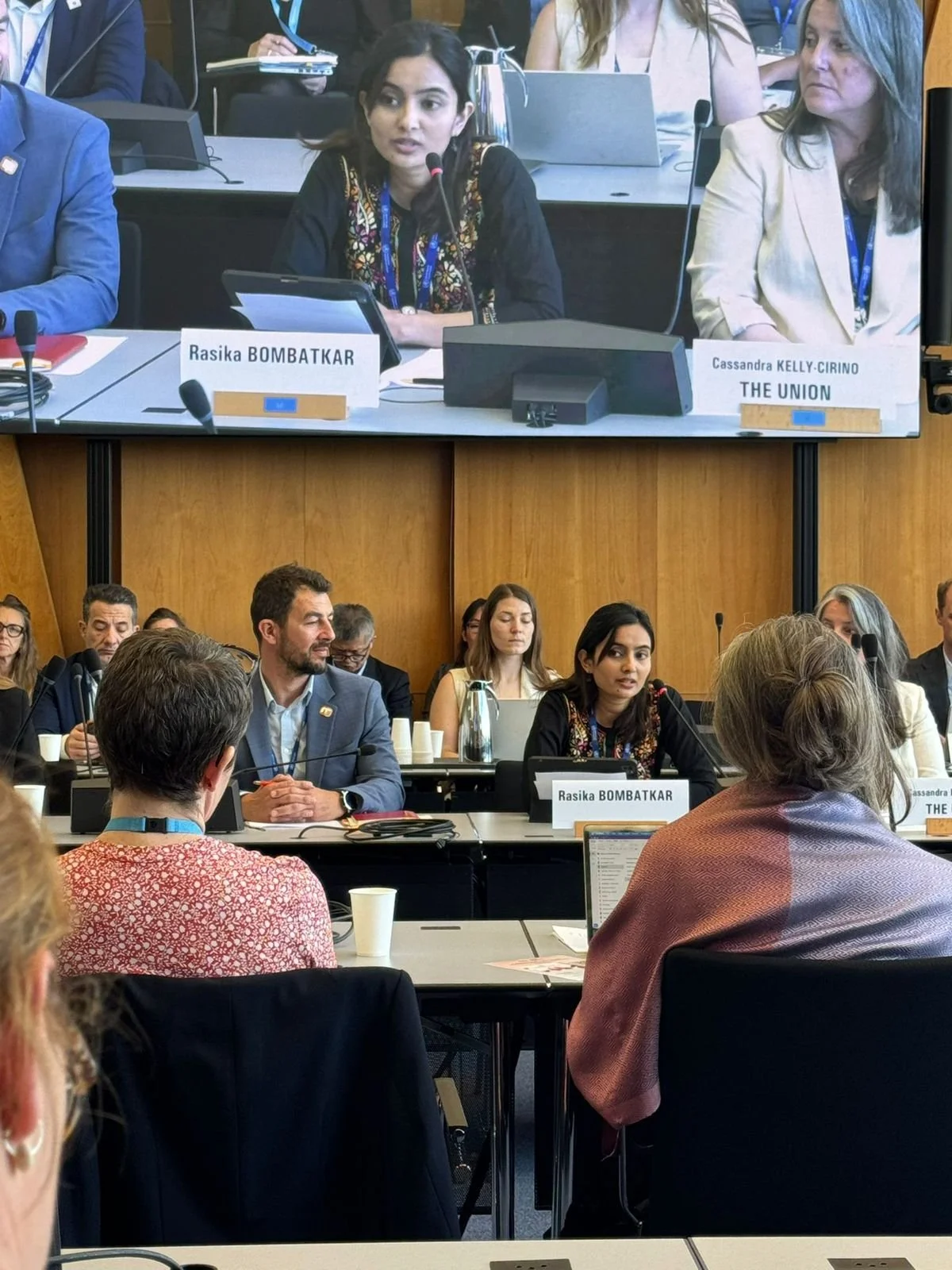 Rasika speaking at the World Health Assembly in Geneva courtesy of the UICC.  She advocates for patients to be more than decorative and emotional stories. We need to be in the rooms where decisions are made.  She sits in a room with a card with name