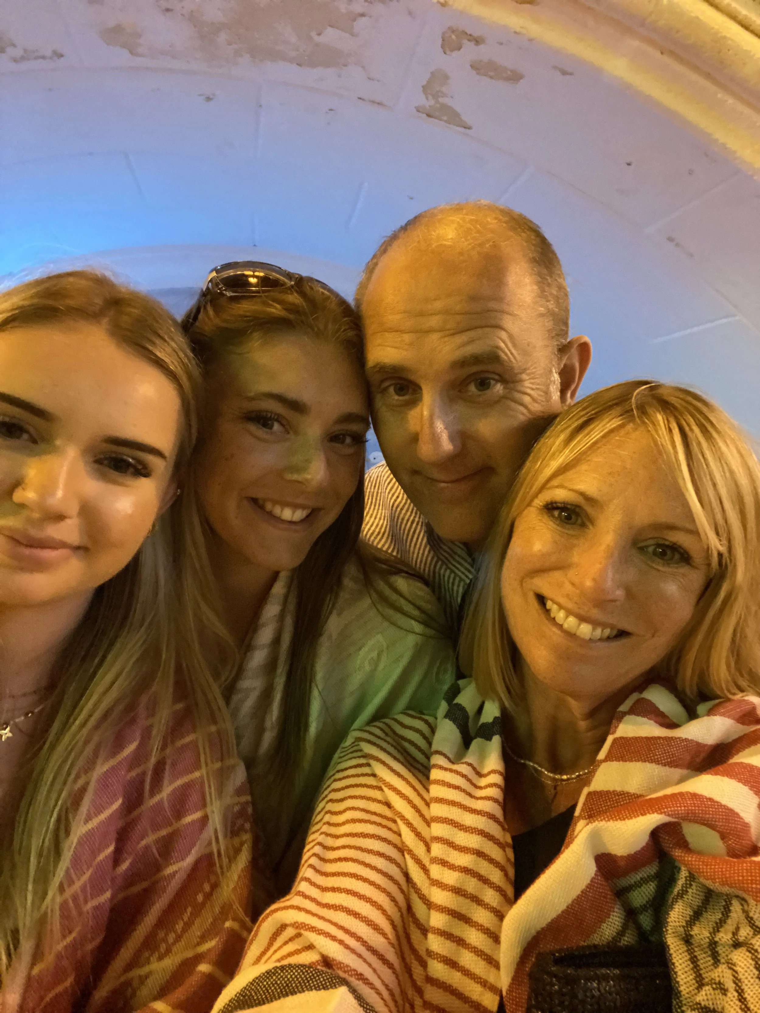 Selfie photo of Natasha, with her husband and two daughters looking a little older now - late teen/early 20s.