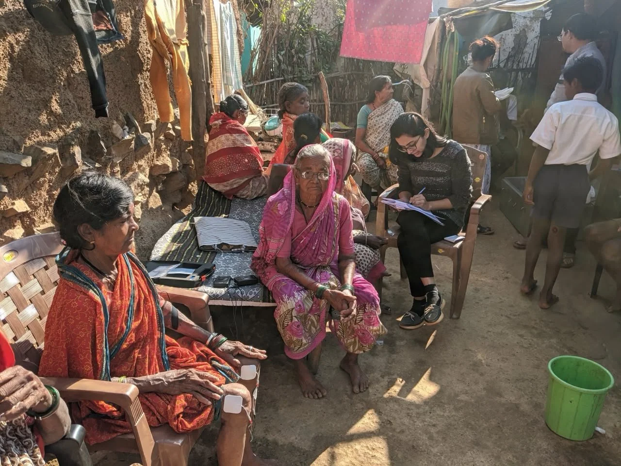 Rasika, before her lung cancer diagnosis, in a remote India village of local people in Indian traditional clothes. She noting this on a chart.
