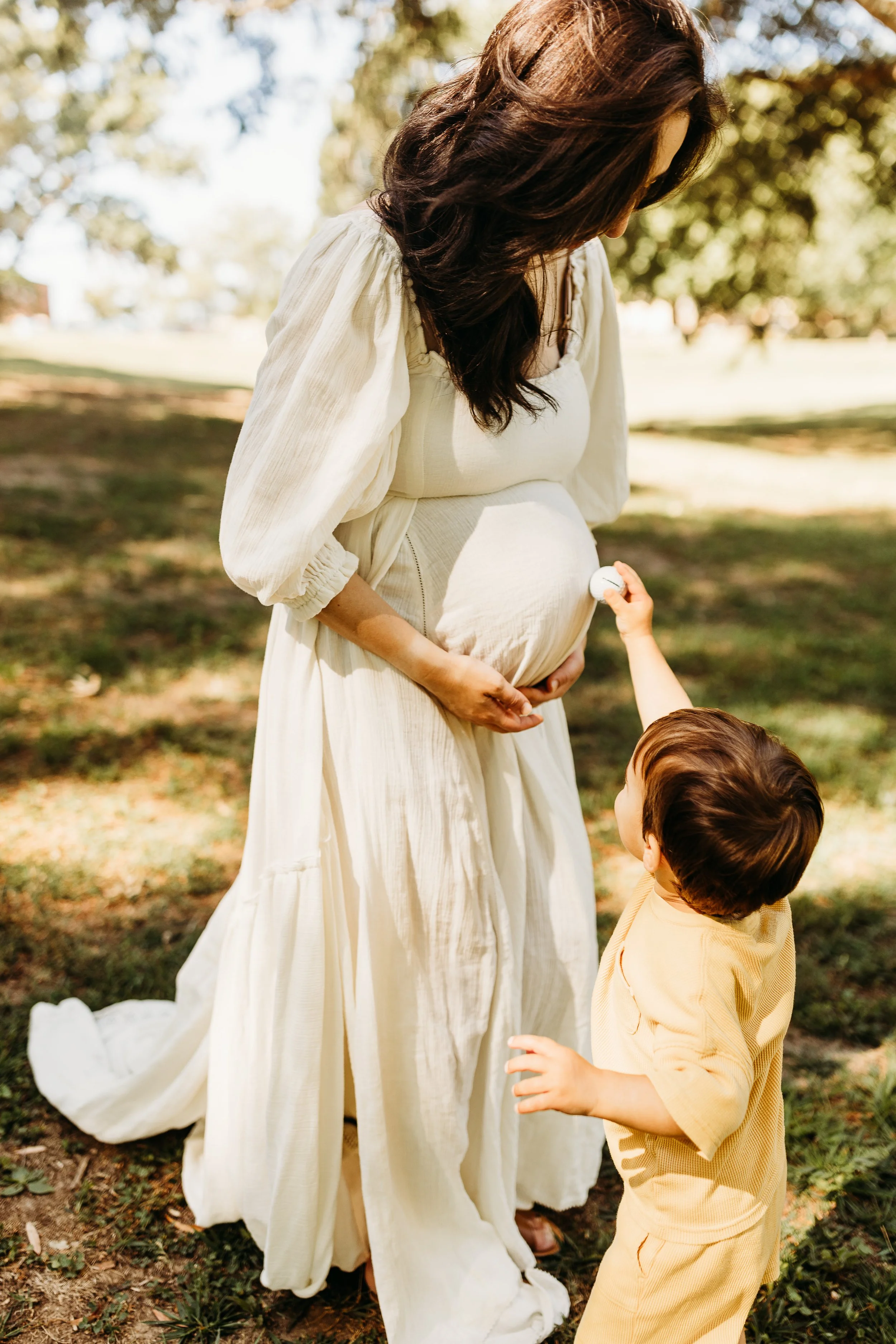 Photo of Mayya heavily pregnant with her toddler touching her baby bump