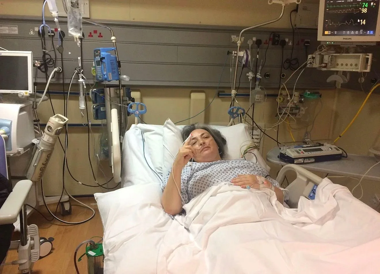 Nichol laying on a hospital bed, with wires around her - post surgery for her lung cancer.