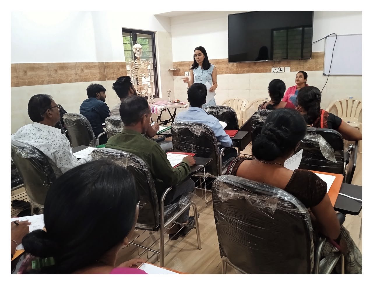 Rasika brought health education to others. Photo of her speaking in front of class room full of adults.