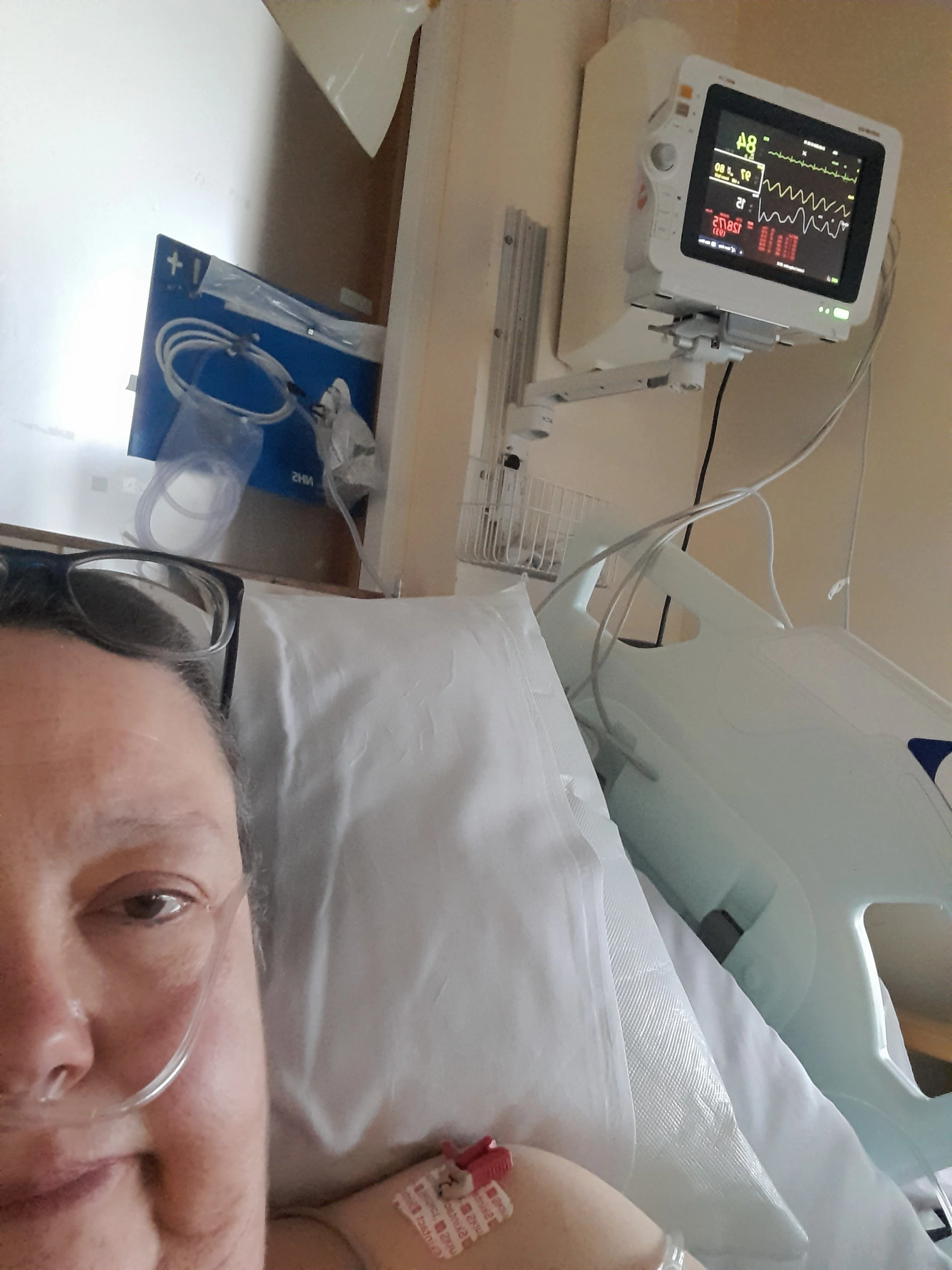 Close up of Allison in hospital with an oxygen cannula and hospital machines behind her.