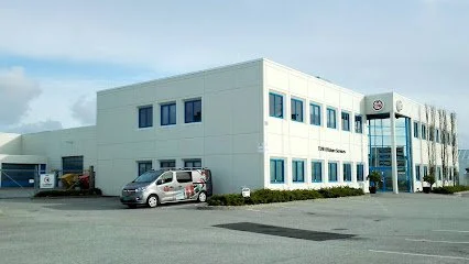 En bygning med Toyota-logo, parkering foran, og en bil.