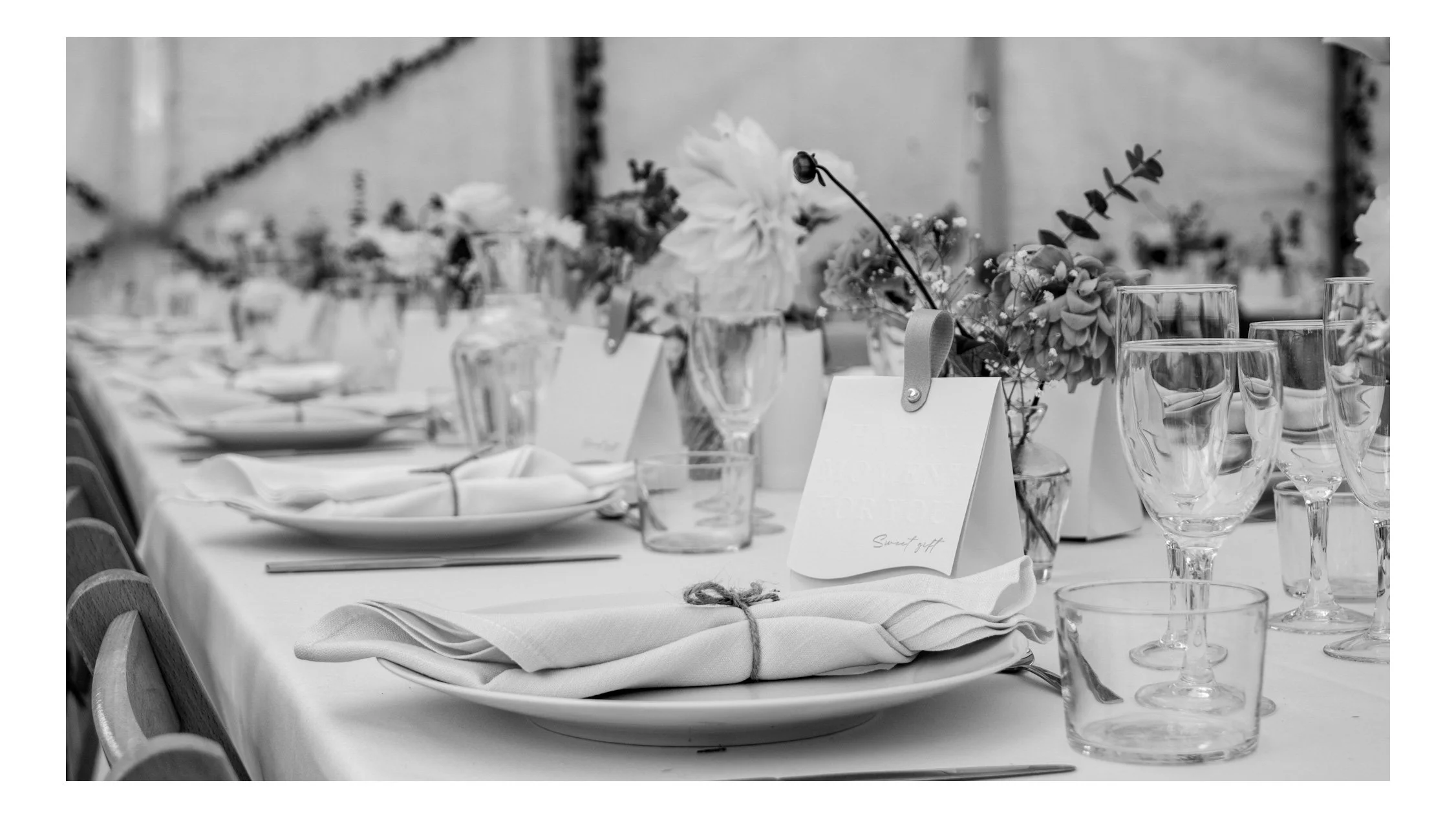 Table de mariage élégamment dressée avec des fleurs, des verres, des assiettes, et des nappes, pour une réception formelle.