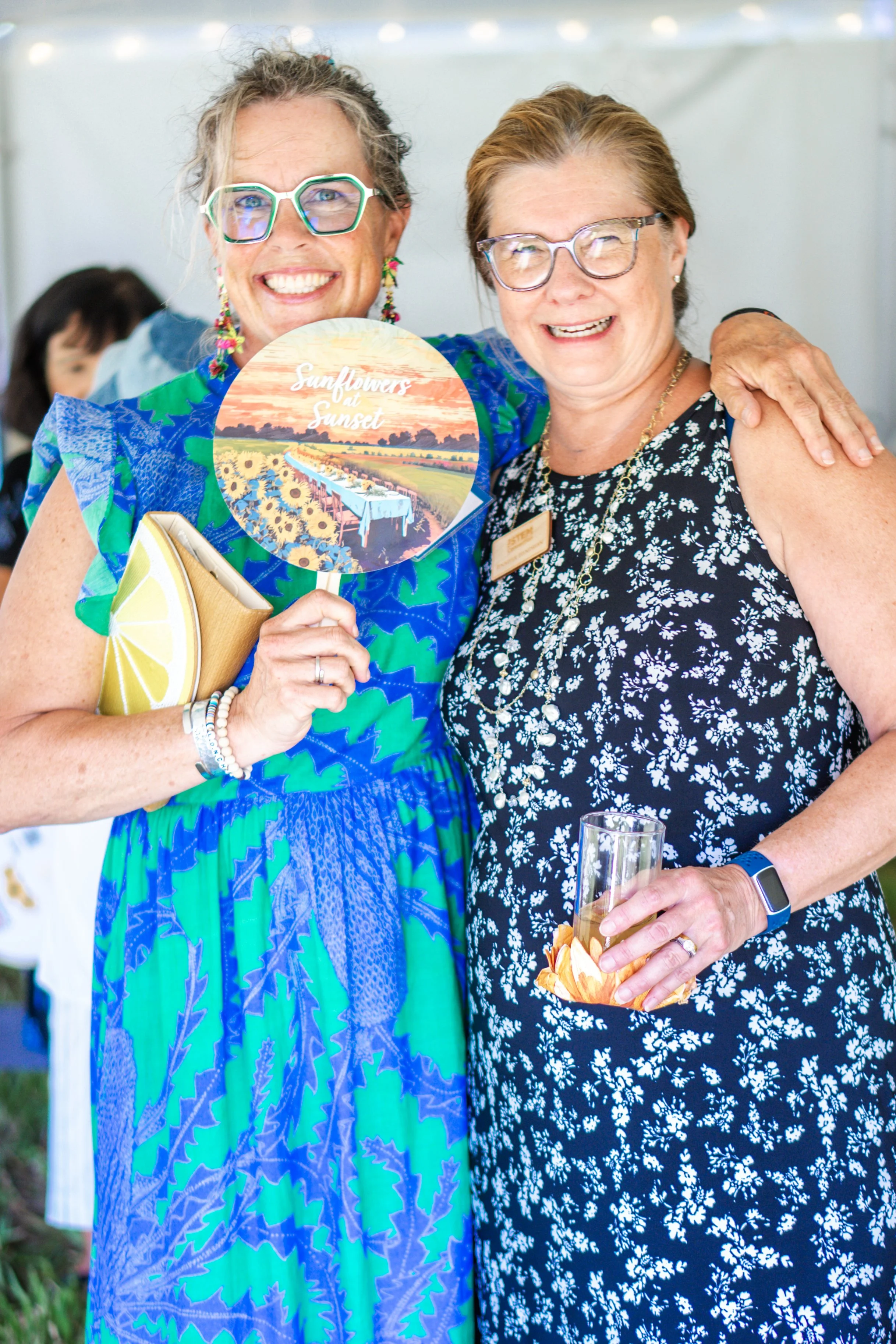 Sunflowers at Sunset guest and The STEM Connection board member smiling and holding a fan.