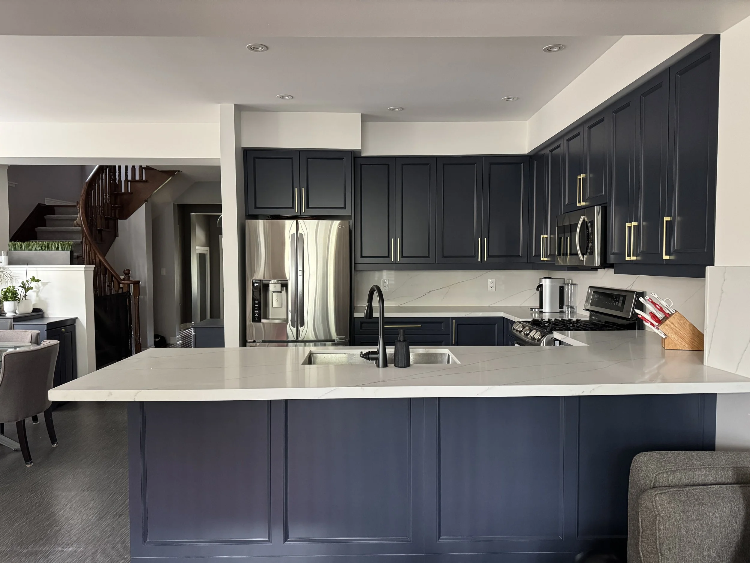 A finished kitchen with deep navy cabinets and a white island top