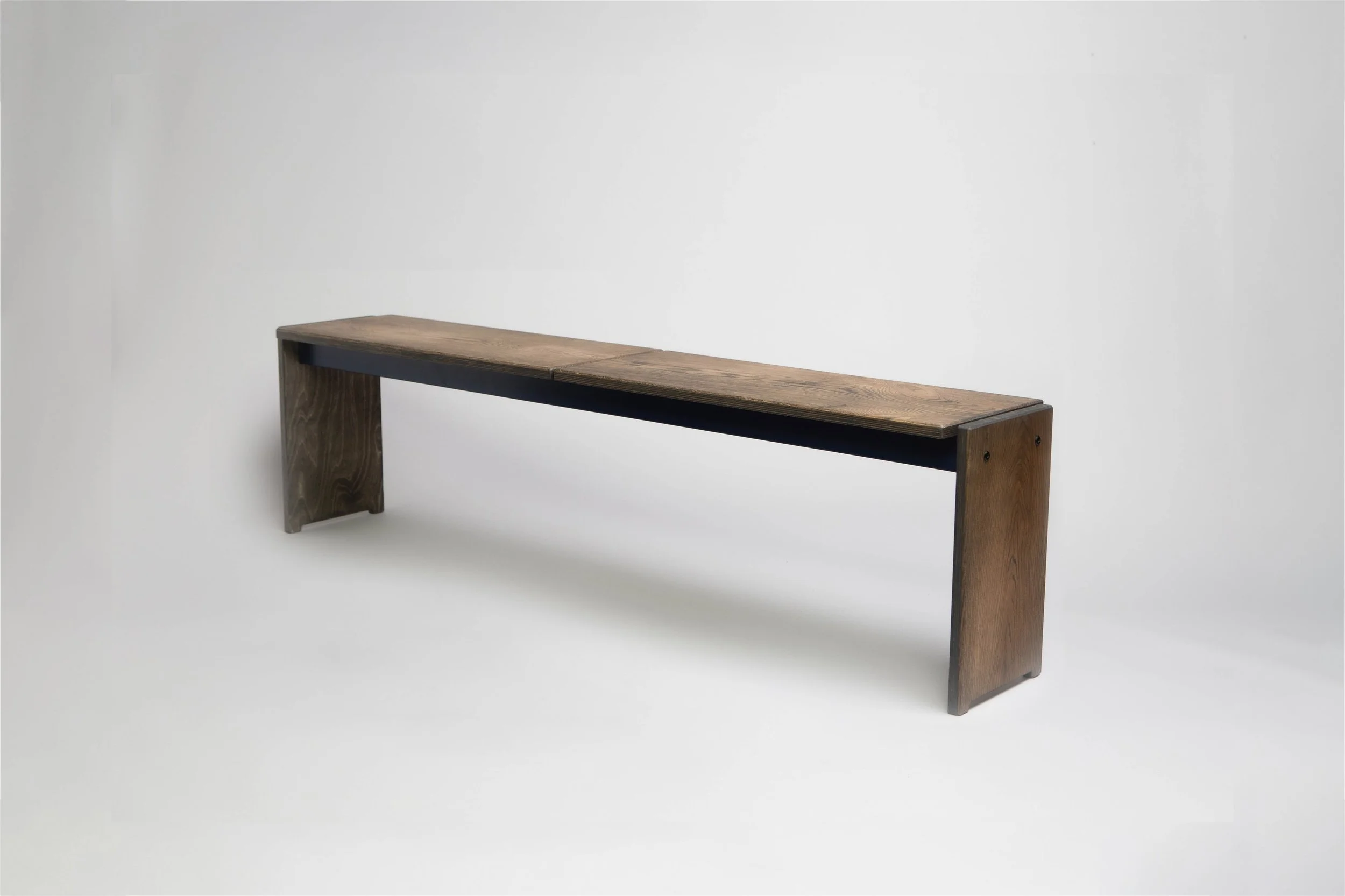 A minimalist wooden bench with a simple, rectangular design and dark legs, set against a plain white background.
