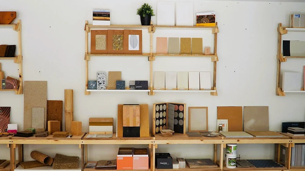 Display of building materials and sample tiles on wooden shelves and tabletop in a showroom