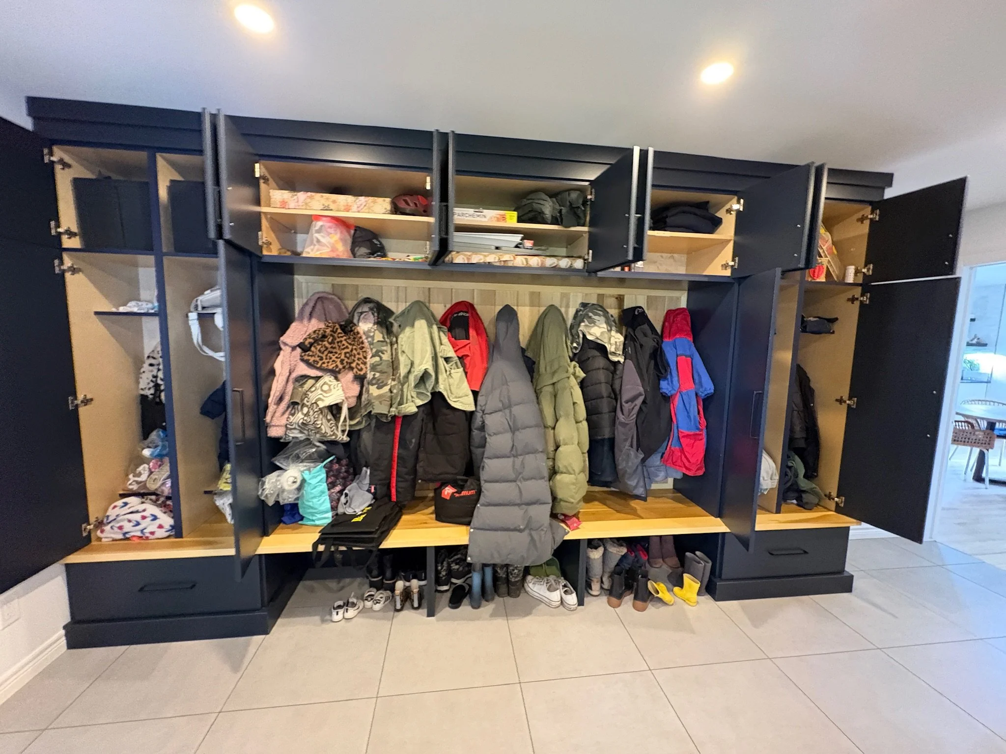 A large black locker with open doors revealing hanging jackets, shoes, and various personal items inside in an indoor setting.