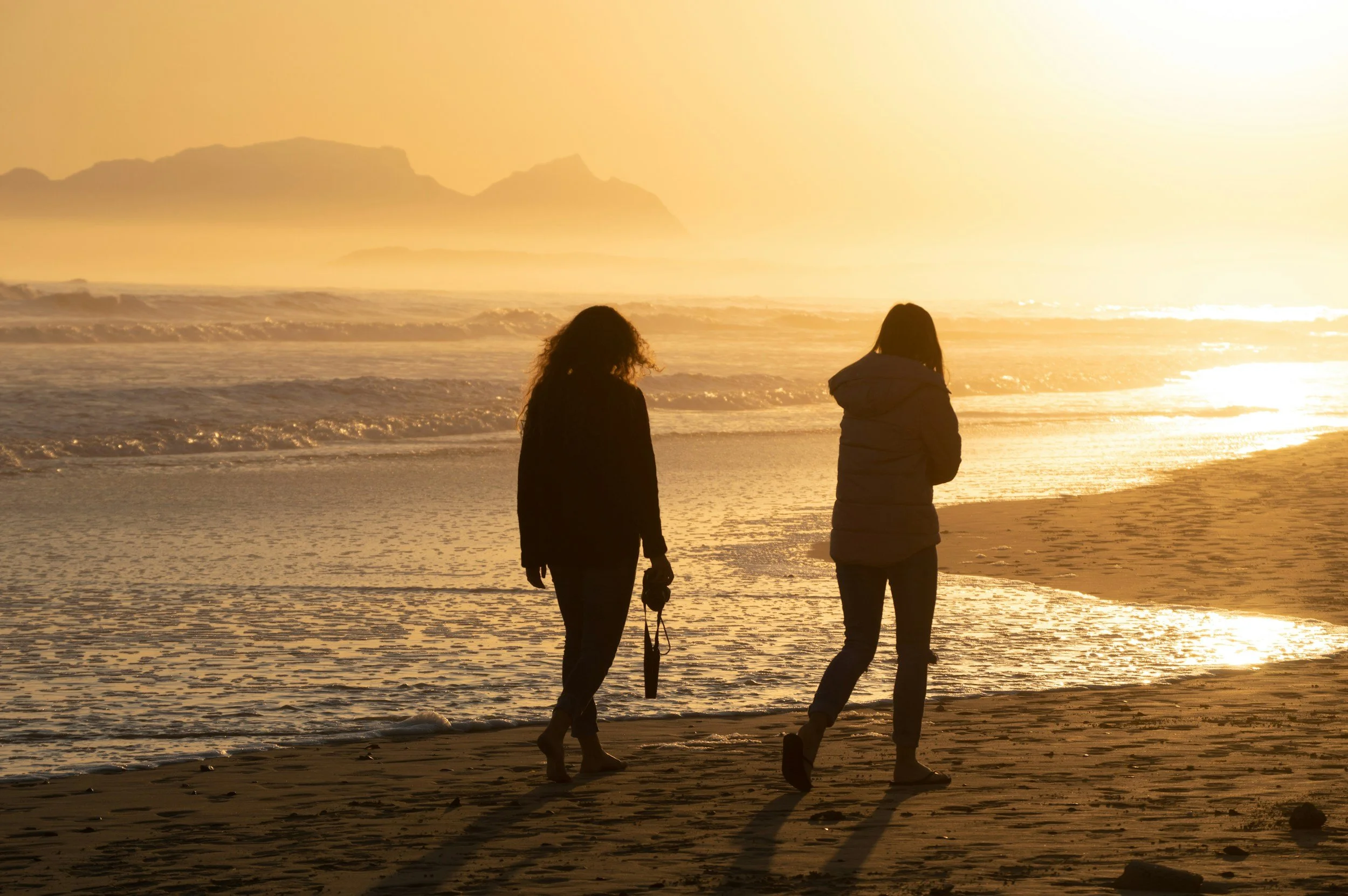 Two female friends walking on beach