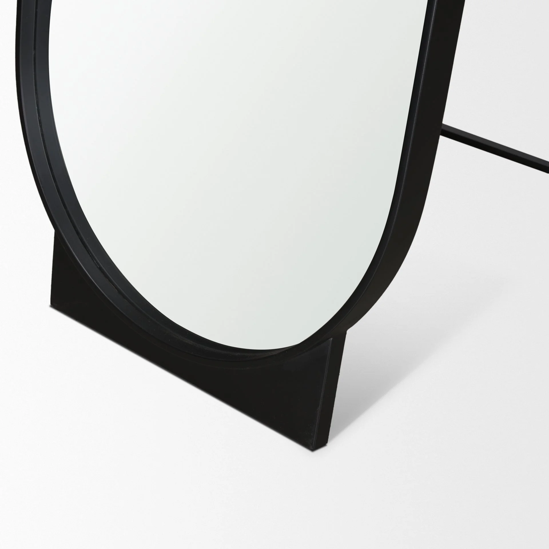 1. Close-up of matte black metal frame and base on oval floor mirror