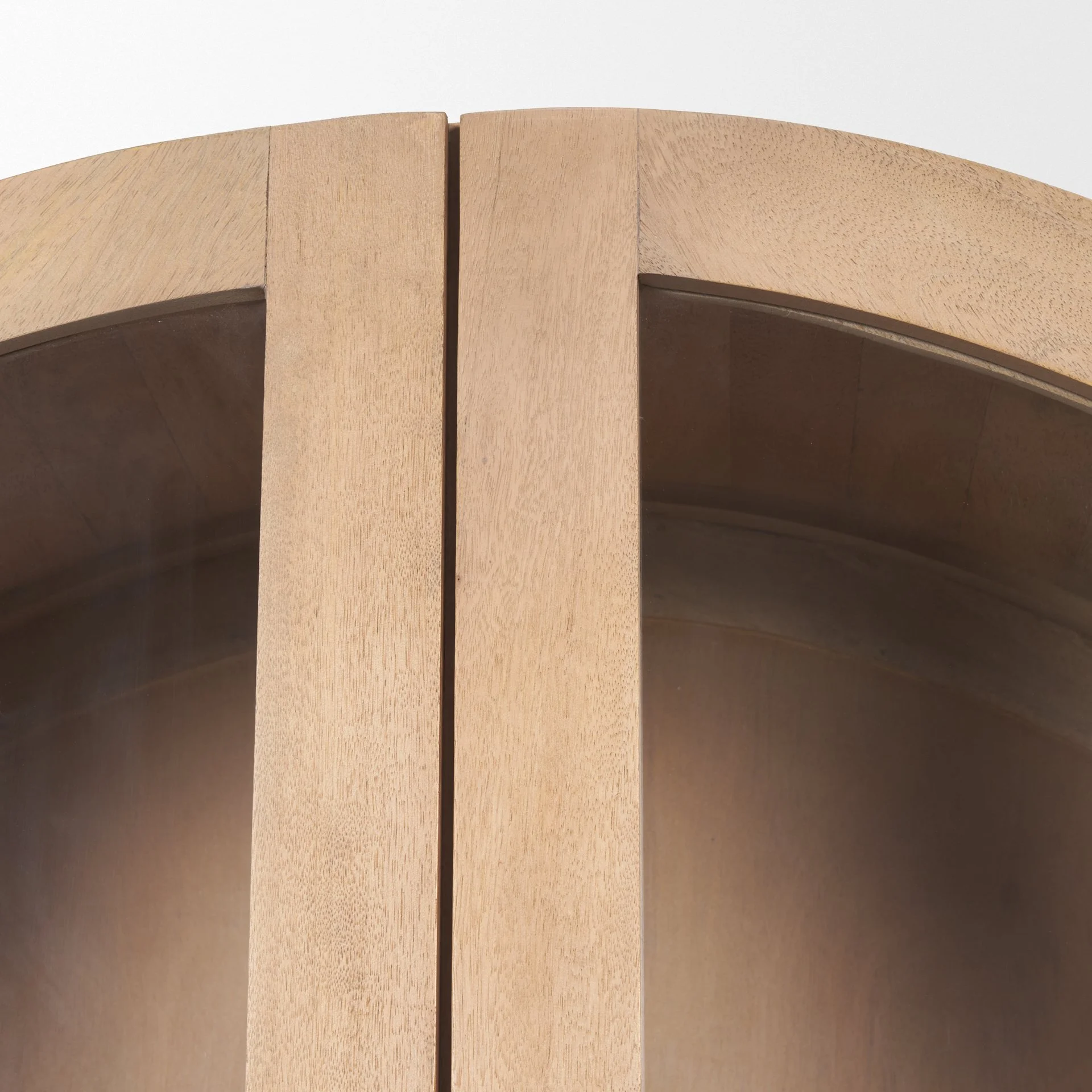 Close up of the top of the 223 arched mango wood display cabinet in light brown finish, with handmade brass knobs and sculptural arched frame.