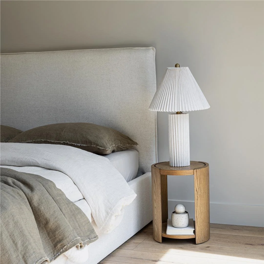 8 Collection side table placed beside bed with layered neutral bedding and soft lighting
