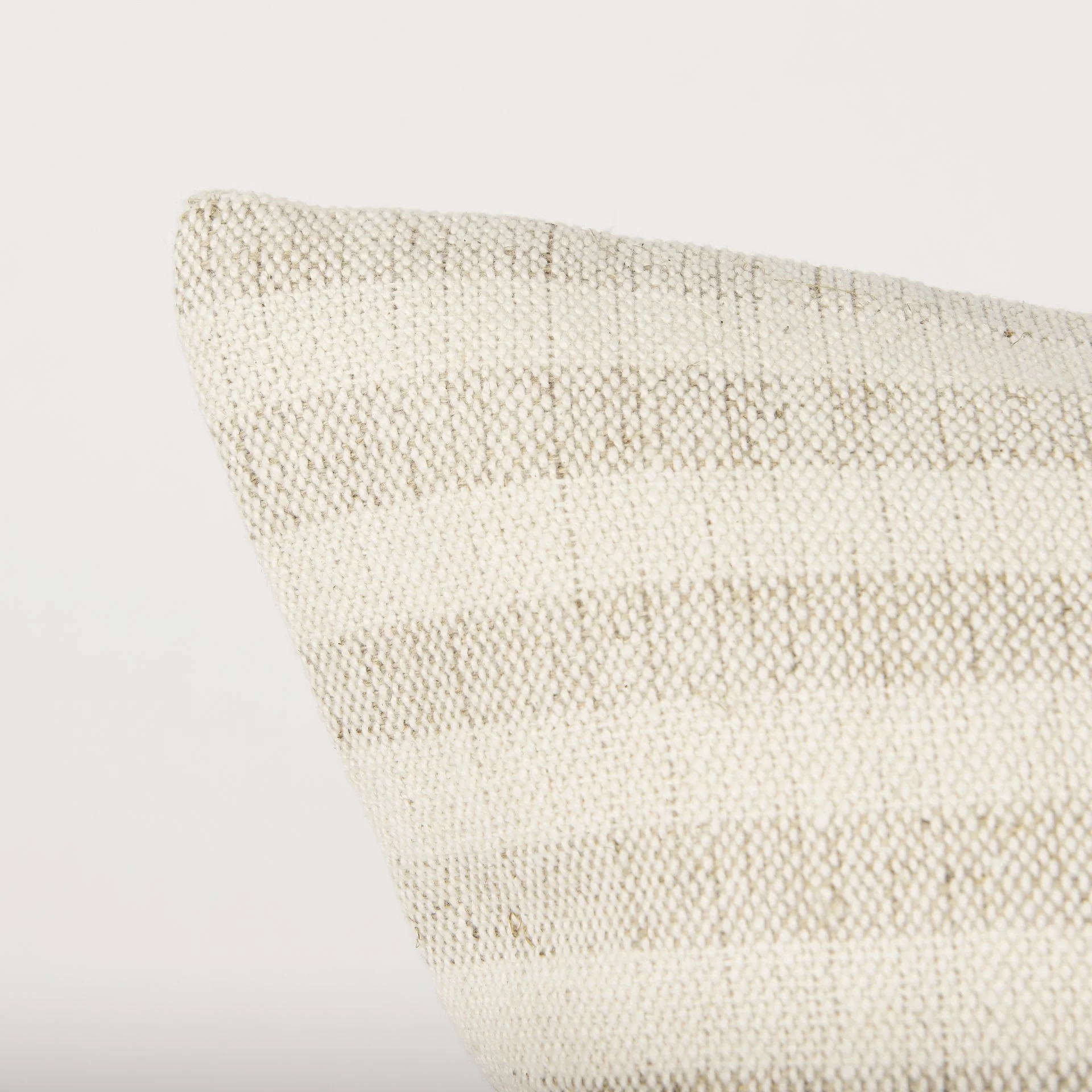 Corner detail of linen cushion cover, cream and beige striped.