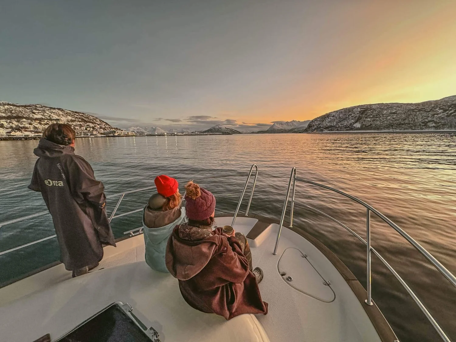 Guests on the bow of the expedition boat in the Norwegian fjords at sunrise