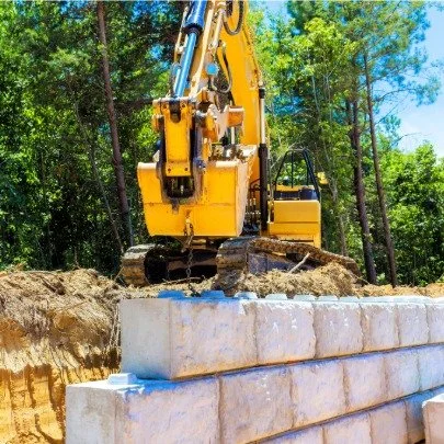 Yellow excavator building a retaining wall in Bend Oregon.