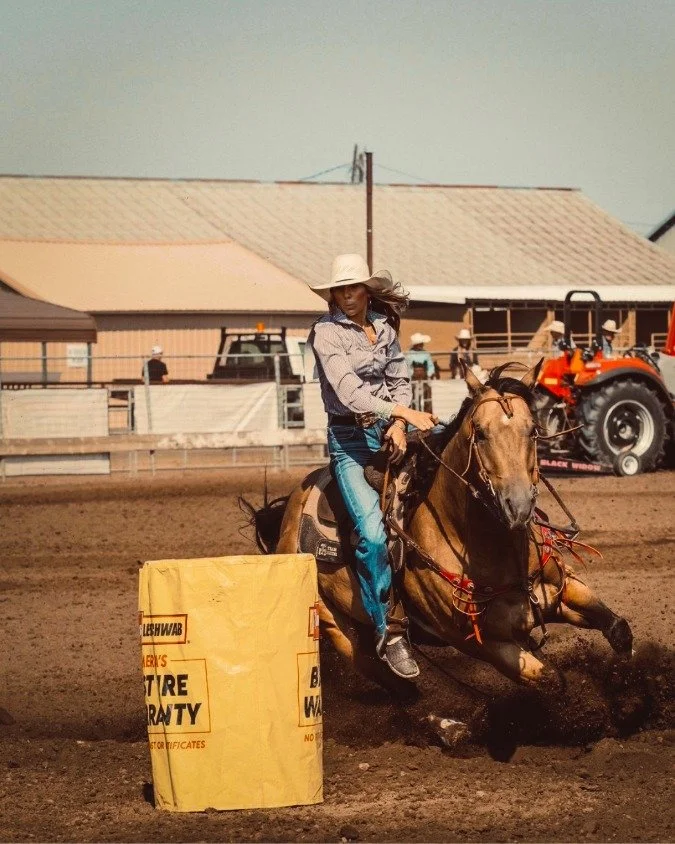 Woman and a horse barrel racing in a Central Oregon equine arena built by an athletic field builders bend oregon.