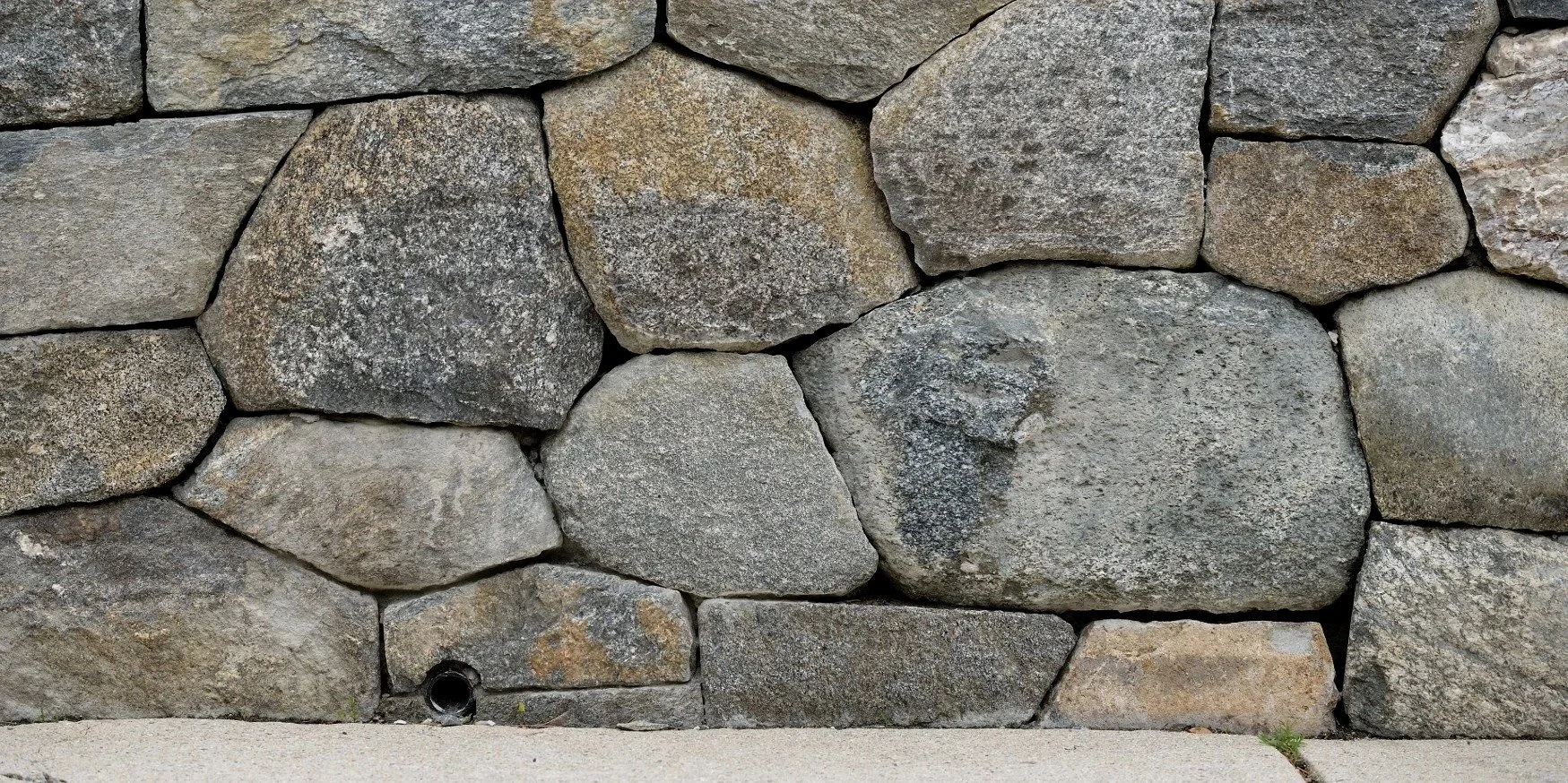 Close-up view of a stone wall built with irregularly shaped stones of various sizes and shades of gray and brown.
