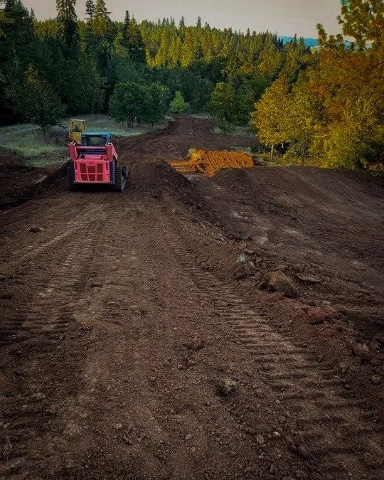 Small red excavator building a dirtbiking track in Central Oregon.