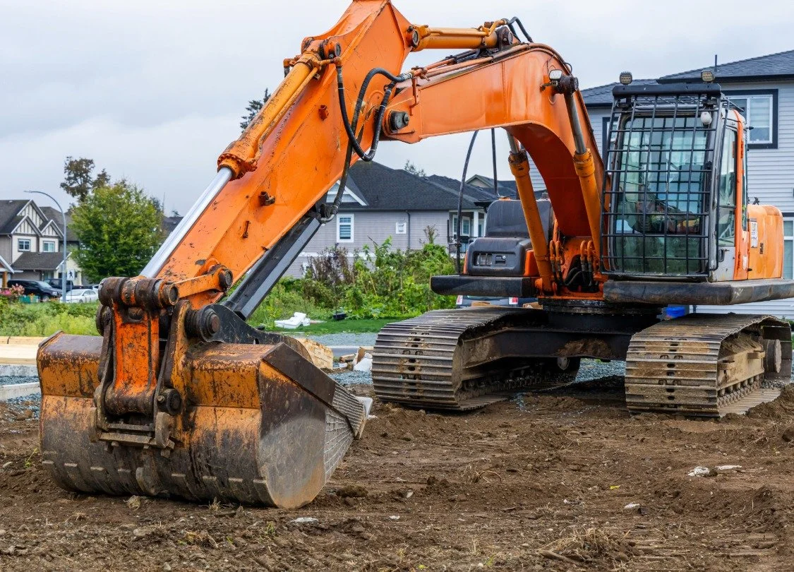 Orange excavator preparing a residential construction site in Bend Oregon.