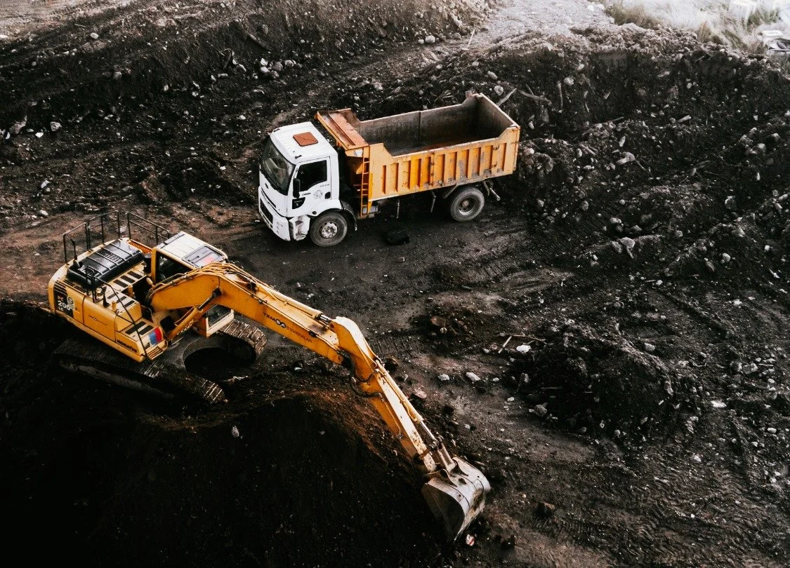 Big Excavator in a commercial excavation site with a dump truck in Bend Oregon.
