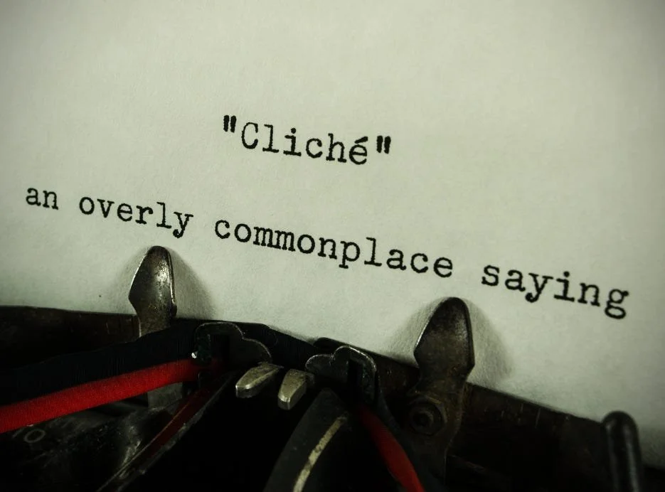 a close up of a type written page still in the type writer. It reads, "Cliche" and on the second line it reads, "an overly commonplace saying."