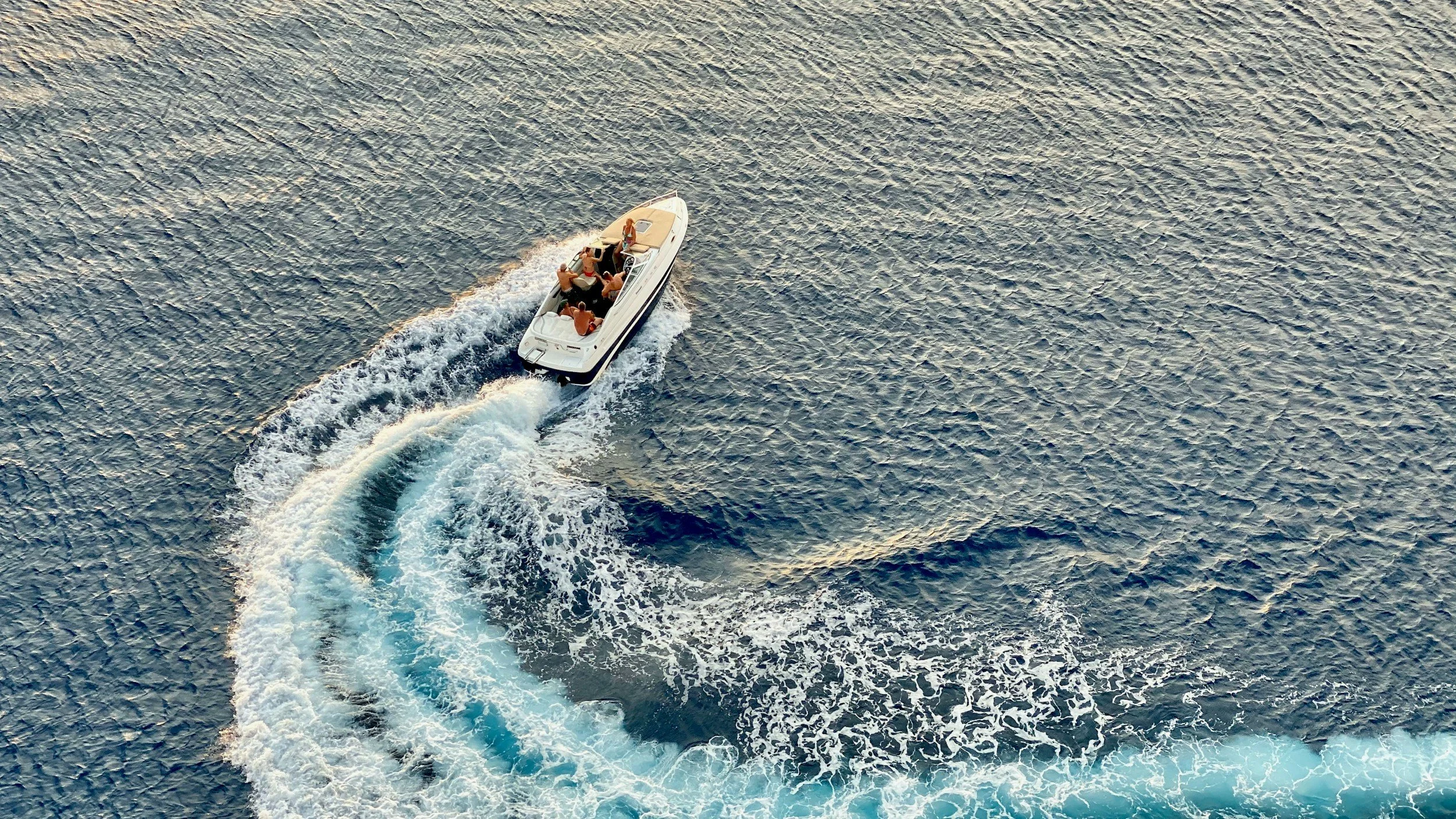 Aerial view of a speedboat making a circular wake on the water.